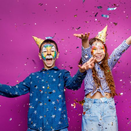 portrait-of-positive-cheerful-little-girl-and-boy-have-fun-isolated-over-violet-color-wall-serpentine-flying